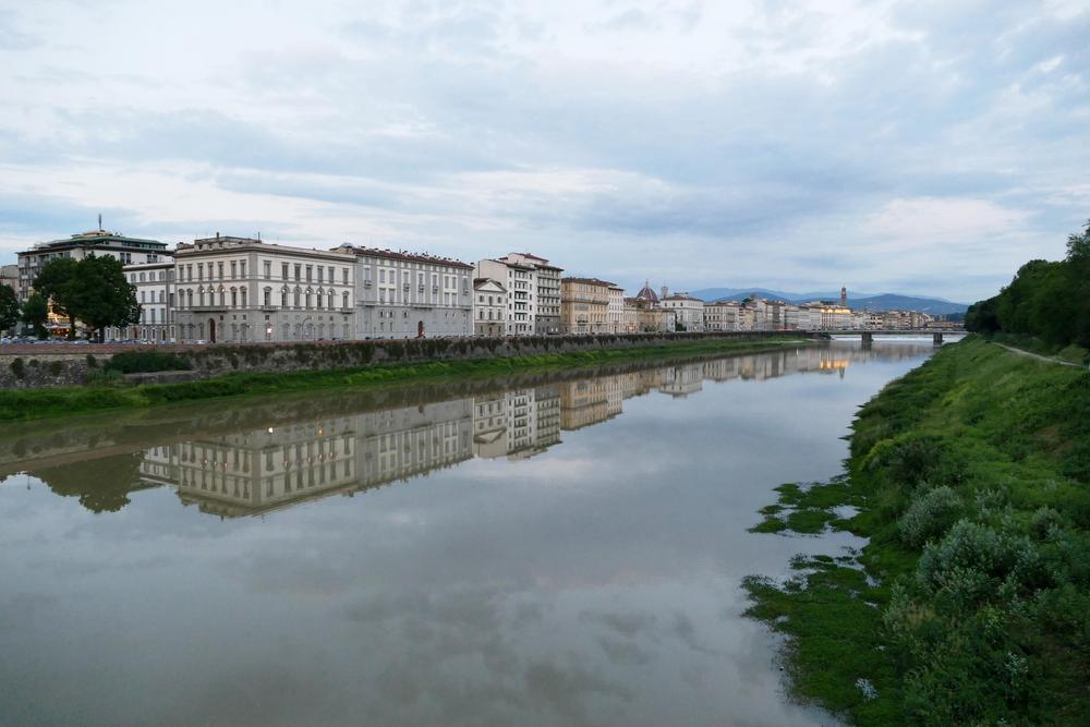 Buildings reflected in the Arno River.