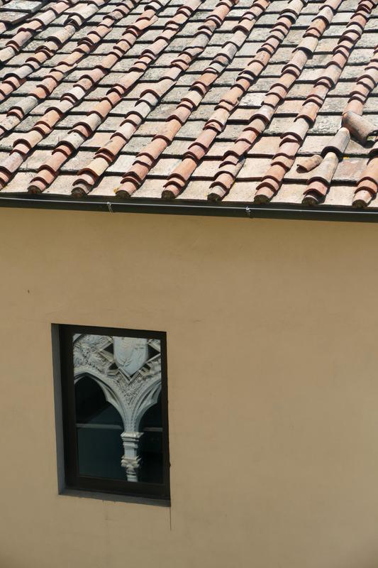 Tile roof and window, with church ornamentation reflected in the window.