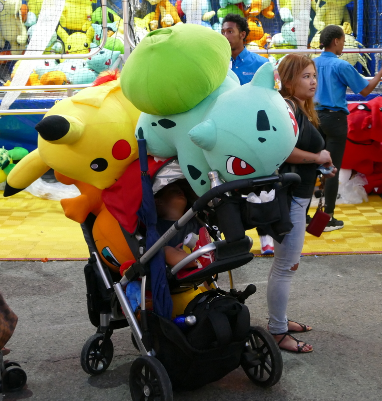 Three huge Pokemon overshadow a sleeping child in a stroller.
