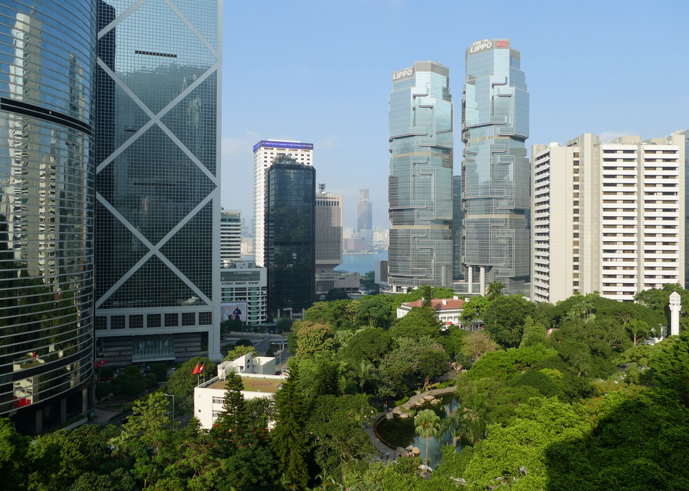 a view over the trees of Hong Kong Park to city buildings, notably the Lippo Centre