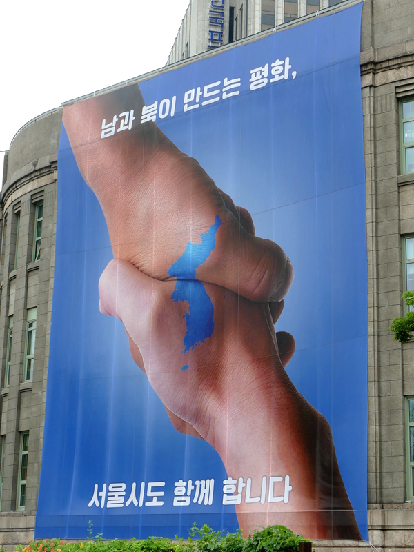 Two hands clasped, each with half of Korea on it so they match and join.