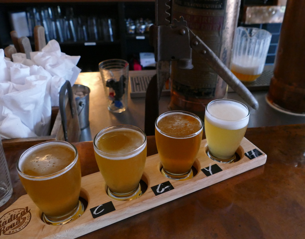 four sample-sized beers in a classic wood flight paddle