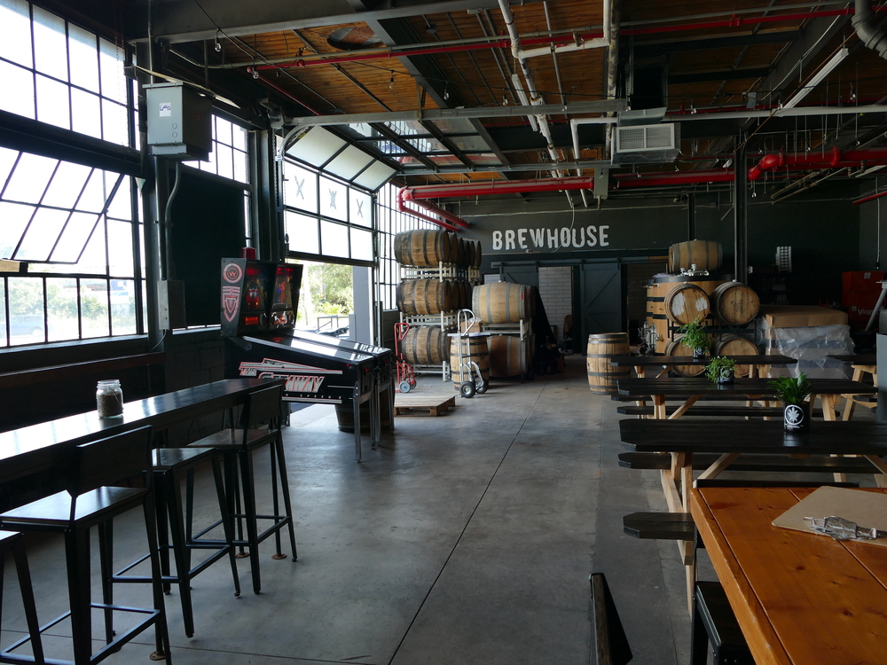 concrete floor, rail with high stools, some picnic tables, two pinball machines, and lots of barrels.