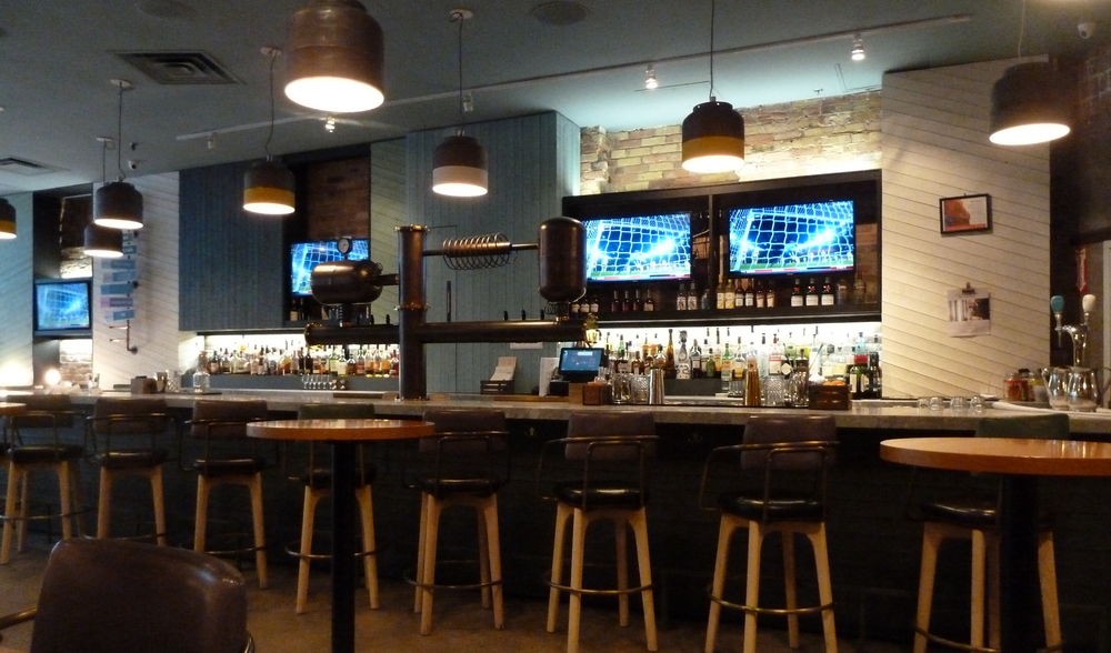 a bar with multiple TVs behind it and fancy beer-dispensing taps