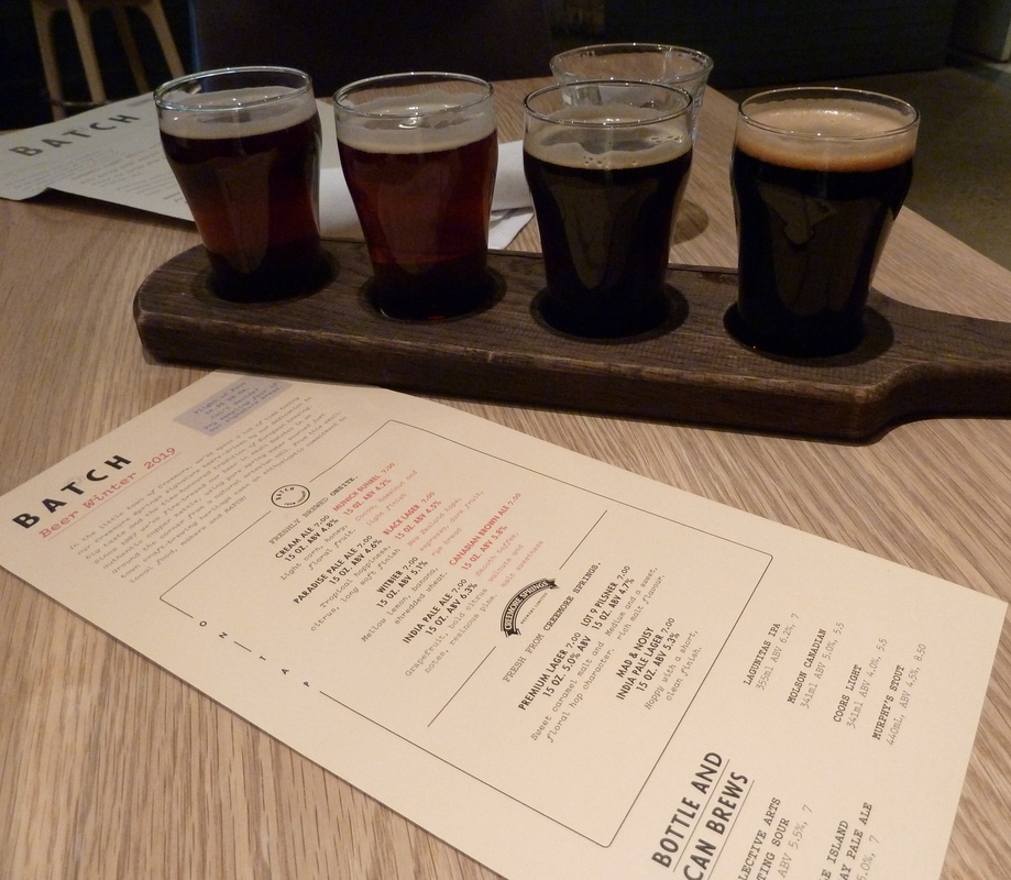 a flight of four beers and an difficult-to-read beer menu