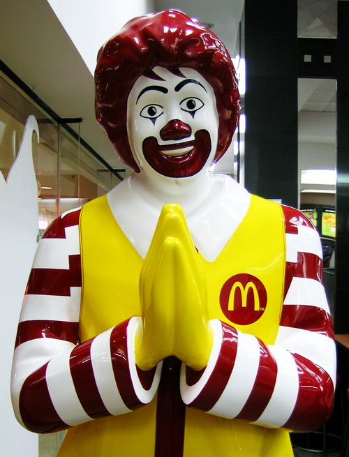 Ronald McDonald bowing namaste at the door of a McDonalds in Thailand