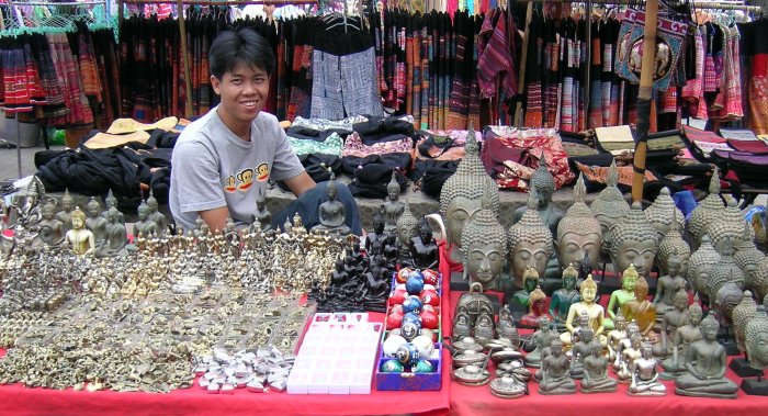 A vendor selling a large variety of brass Buddha images.