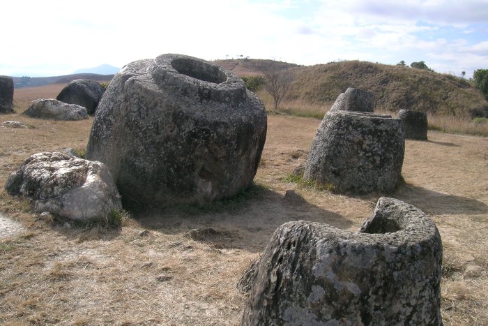 Several large stone jars on the dry grass hills.