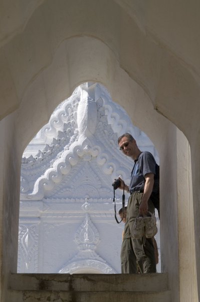 Me in a temple in Myanmar, holding my shoes and camera.