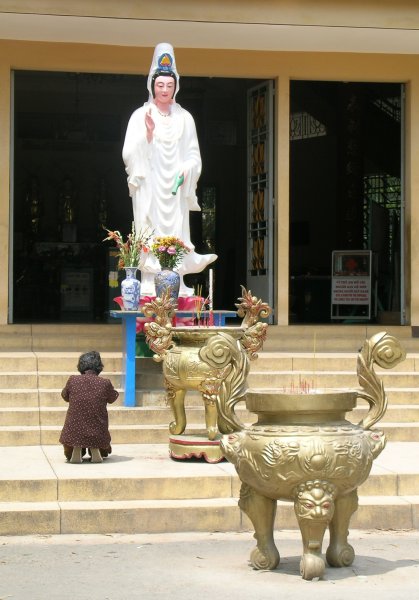 A woman kneeling in prayer on the temple steps