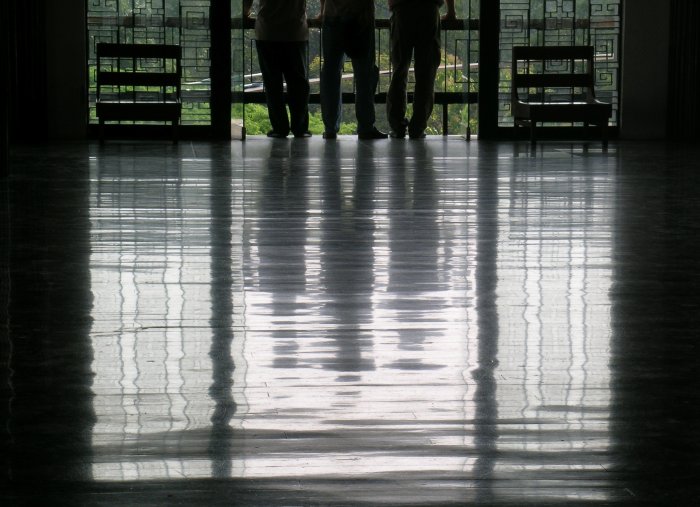 A floor reflection of three men standing in a window.