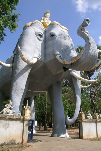 A massive three-headed elephant sculpture stands over the gate to a temple