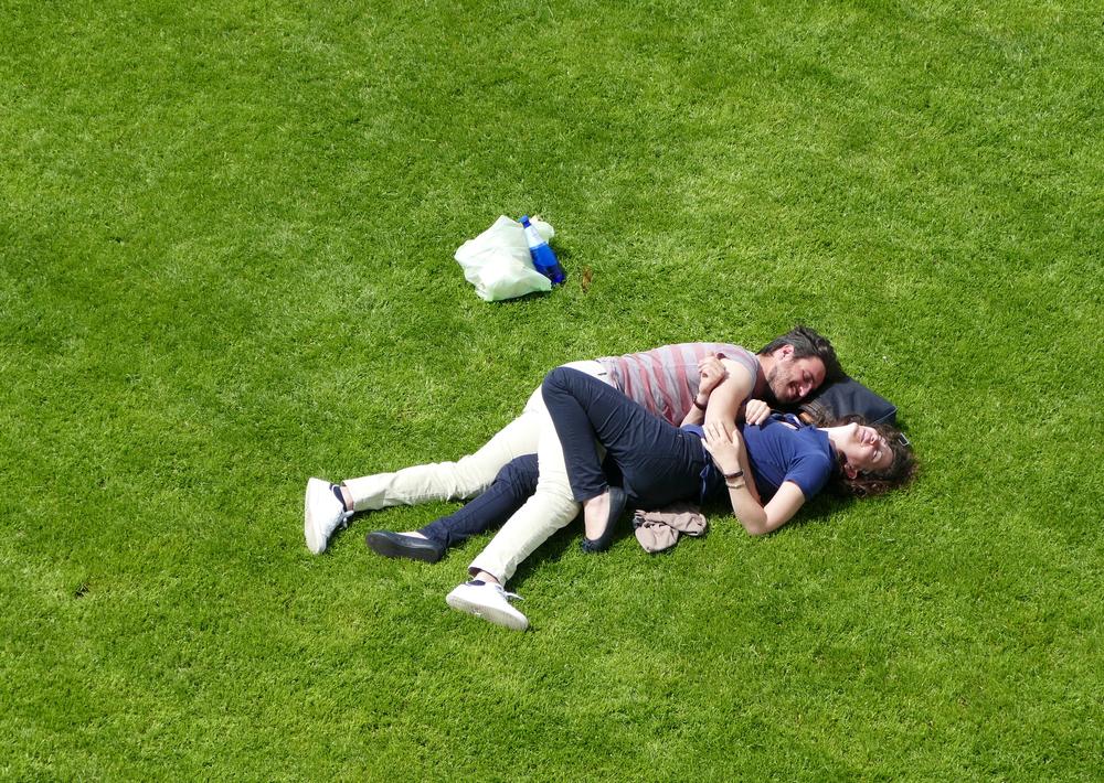 A couple lying together on the grass.